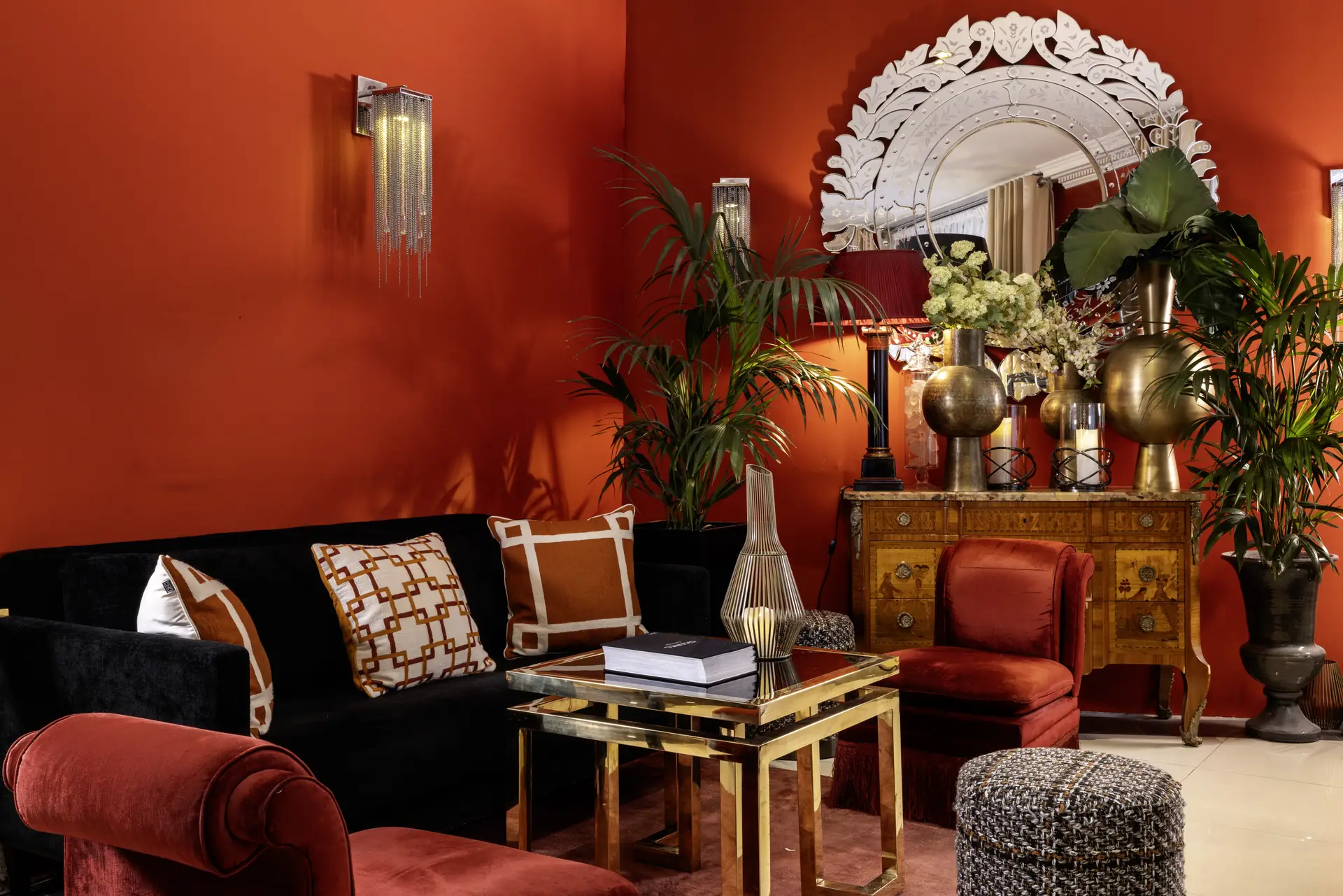 Canapé de velours noir et fauteuil rouge devant un miroir vénitien et une commode dorée